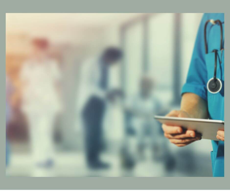 Person standing in hospital hallway with stethoscope and chart